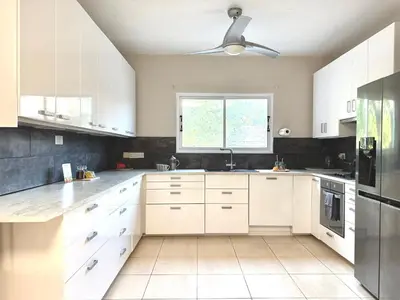 a kitchen with white cabinets and a ceiling fan at Onyx Beach Villa - Cozy 2BR - Walk to Beach in Meneou