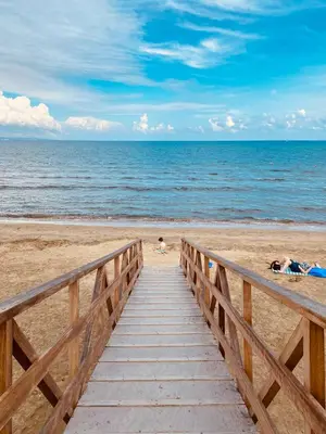 a wooden pathway to the beach with people laying on the sand at Calypso Historic Village House in Limassol