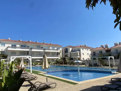 a swimming pool with chairs and umbrellas in front of a building at Amalfi Suite at Mythical Sands Resort in Paralimni