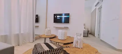 a living room with two tables and a tv at Amalfi Suite at Mythical Sands Resort in Paralimni