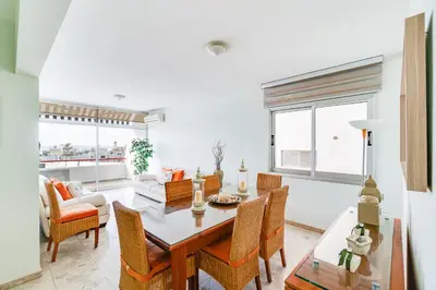 a dining room and living room with a table and chairs at Family Friendly 2-Bed on Limassol Seafront in Limassol