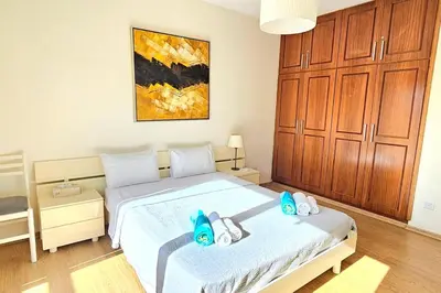 a bedroom with a bed with blue shoes on it at Dasoudi Pecora Beach Apartment in Limassol