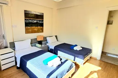 a bedroom with two beds with blue and white sheets at Dasoudi Pecora Beach Apartment in Limassol