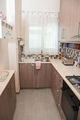 a kitchen with wooden cabinets and a sink and a window at Bluewave Apartment in Pyla