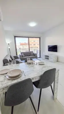 a living room with a table with chairs and a couch at Pool Citylux Apartment in Larnaka
