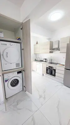 a white kitchen with a washer and dryer in it at Pool Citylux Apartment in Larnaka