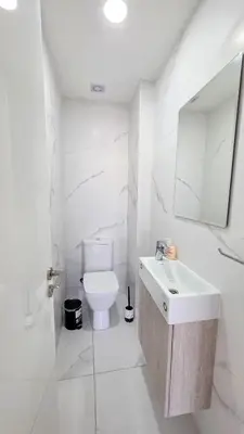 a white bathroom with a sink and a toilet at Pool Citylux Apartment in Larnaka