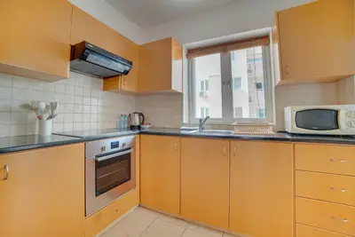 a kitchen with wooden cabinets and a microwave and a sink at Cozy Mackenzie Getaway in Larnaka