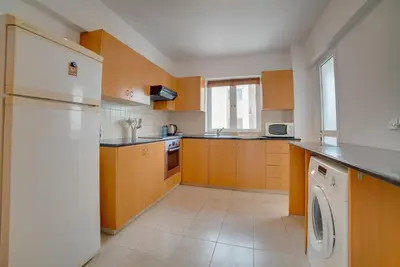 a kitchen with wooden cabinets and a white refrigerator at Cozy Mackenzie Getaway in Larnaka