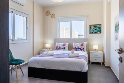 a bedroom with a large bed with two windows at Ondo 2-Bedroom Apartment in Larnaka