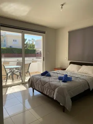 a bedroom with a bed and a balcony with a table at Nissi Bliss Apartment in Ayia Napa