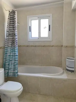 a bathroom with a tub and a toilet and a window at Nissi Bliss Apartment in Ayia Napa
