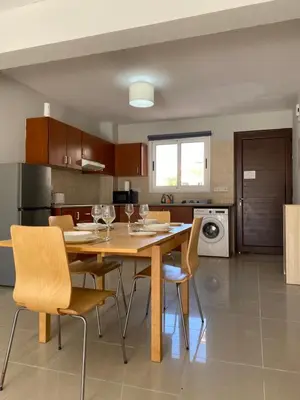 a kitchen with a wooden table and chairs in a kitchen at Nissi Bliss Apartment in Ayia Napa