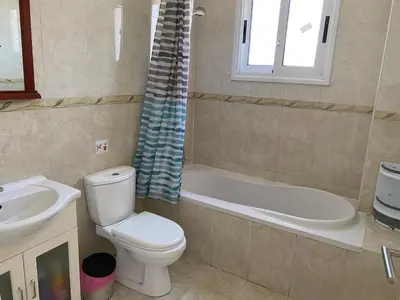 a bathroom with a toilet and a tub and a sink at Nissi Bliss Apartment in Ayia Napa
