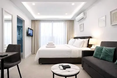a hotel room with a bed and a living room at White Arches Studio Suite by TrulyCyprus in Limassol