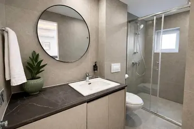 a bathroom with a sink and a shower and a mirror at White Arches Studio Suite by TrulyCyprus in Limassol
