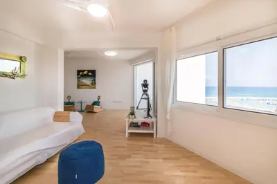 a living room with a couch and a large window at Limanaki Beach Aparment in Larnaka