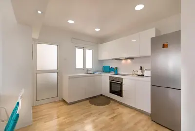 a kitchen with white cabinets and a refrigerator at Limanaki Beach Aparment in Larnaka