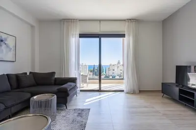 a living room with a couch and a large window at Pearl Beach Luxury Family Suite in Limassol