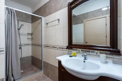 a bathroom with a sink and a shower and a mirror at Beachfront Luxury Living Limassol in Limassol