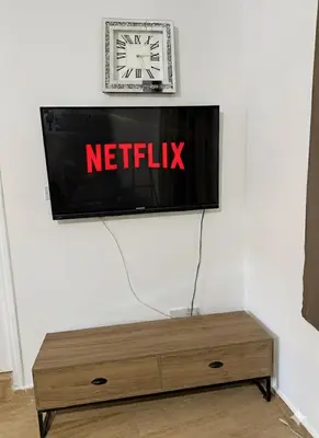 a television on a wall with a clock on it at Villa Keskin - Girne in Ayios Ioannis
