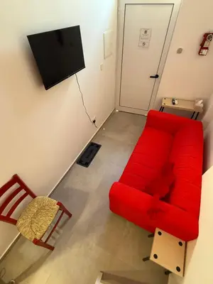 a living room with a red couch and a chair at RED Cabin-Larnaca Centrum in Larnaka