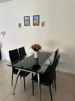 a glass table with black chairs and a vase with flowers at 2 Bedroom Penthouse Apartment With Swimming Pool in Kiti