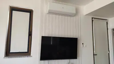 a tv on a wall with a mirror and a window at Ruach Villa in Paralimni