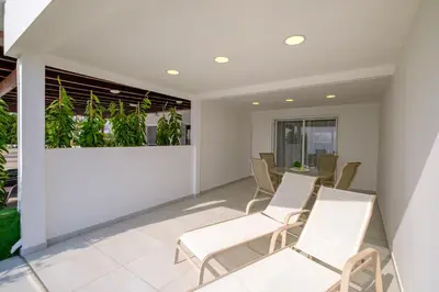 a room with white chairs and plants on the wall at Wavestone Beachfront House in Meneou