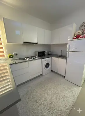 a kitchen with white cabinets and a washing machine at Modern Smart-Home Studio Pools Gym Terrace View in Paralimni