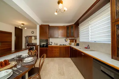 a kitchen with wooden cabinets and a table with chairs at 3 bedroom flat central, beach, walking streets in Limassol