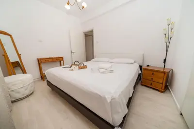 a bedroom with a large white bed and a dresser at 3 bedroom flat central, beach, walking streets in Limassol