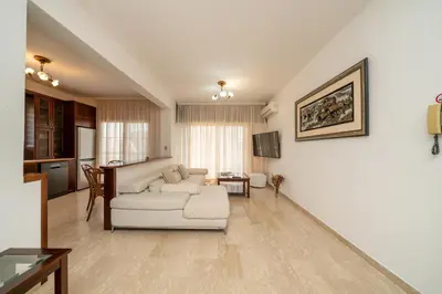 a living room with a white couch and a kitchen at 3 bedroom flat central, beach, walking streets in Limassol