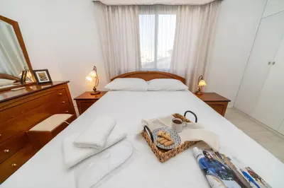a bedroom with a bed with white sheets and towels at 3 bedroom flat central, beach, walking streets in Limassol