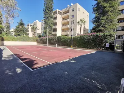 a tennis court in a parking lot in front of a building at Lux studio apartment in Limassol