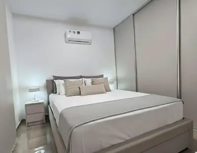 a bedroom with a large bed with a white wall at Luxury Beach Villa 2 min Walk to Sea & Airport in Meneou