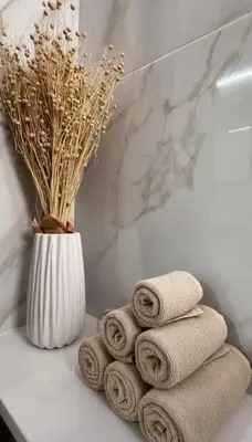 a pile of towels on a bathroom counter with a vase at Luxury Beach Villa 2 min Walk to Sea & Airport in Meneou