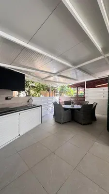 a patio with a table and chairs under a roof at Luxury Beach Villa 2 min Walk to Sea & Airport in Meneou