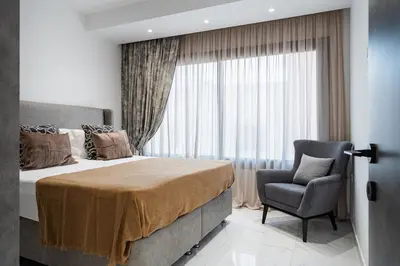 a bedroom with a bed and a chair and a window at Casino & Mall Luxury Jacuzzi Penthouse Suite in Limassol
