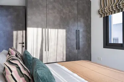 a bedroom with a bed with gray cabinets and a window at Casino & Mall Luxury Jacuzzi Penthouse Suite in Limassol