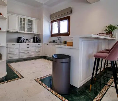 a kitchen with white cabinets and a trash can at Cyprus Sunbay Retreat in Ayia Napa