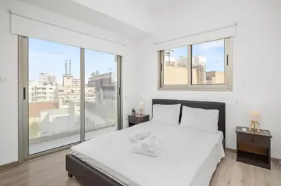a white bedroom with a bed with two towels on it at Downtown City View 2 Bedroom Apartment in Larnaka