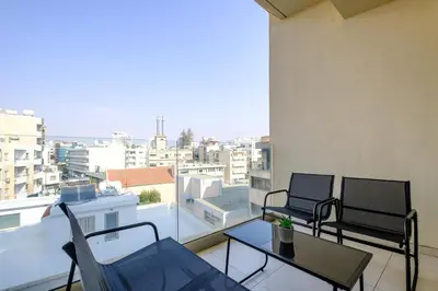 two chairs and a table on a balcony with a view at Downtown City View 2 Bedroom Apartment in Larnaka