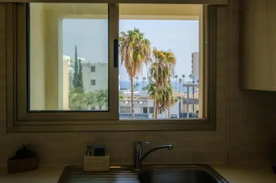 a kitchen sink with a view of a palm tree at Downtown City View 2 Bedroom Apartment in Larnaka