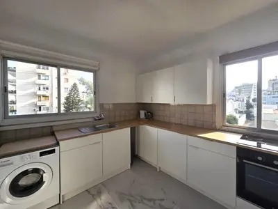a kitchen with white cabinets and a washing machine at City Heart Residence by Staycom in Nicosia