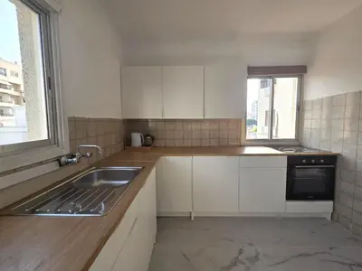 a kitchen with white cabinets and a sink and a window at City Heart Residence by Staycom in Nicosia