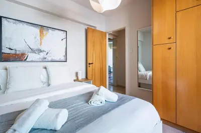 a bedroom with a large white bed with a wooden cabinet at Calina - 3BR Apt W Pool & Balcony in Mackenzie in Larnaka