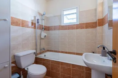 a bathroom with a toilet and a tub and a sink at Calina - 3BR Apt W Pool & Balcony in Mackenzie in Larnaka