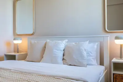 a bedroom with a bed with white pillows and two lamps at Calina - 3BR Apt W Pool & Balcony in Mackenzie in Larnaka