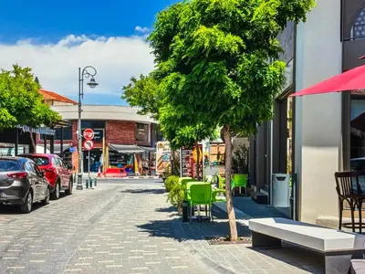 a street in a town with a tree and chairs at Super Views Larnaca in Larnaka